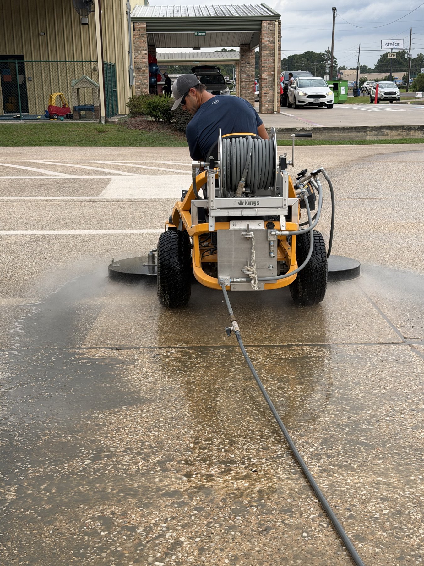 Concrete mid-clean showing the sharp line between dirty and cleaned surface as The Beast passes over it