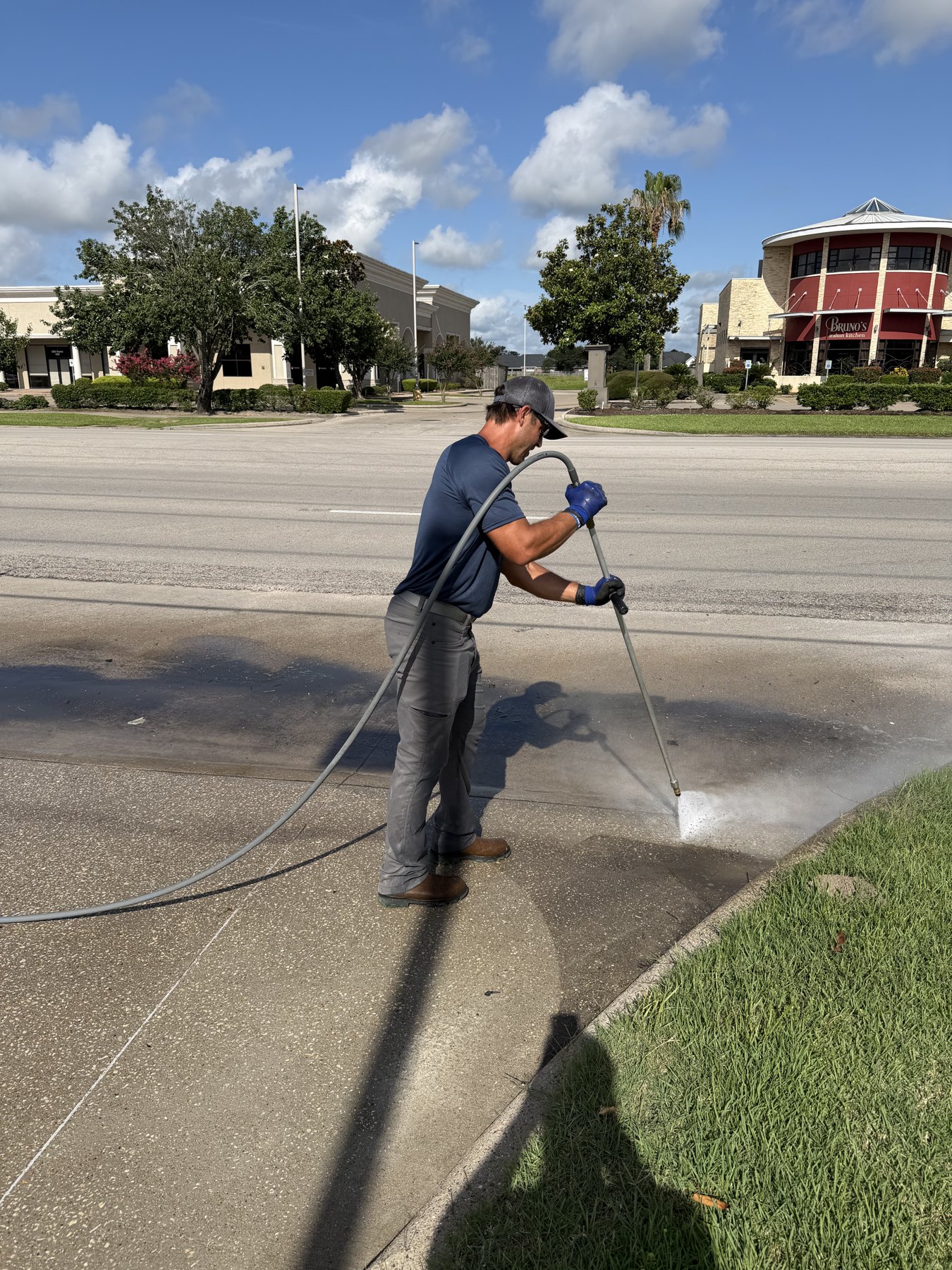 Ryan O'Neal hand-detailing a curb edge with a pressure wand after the ride-on pass